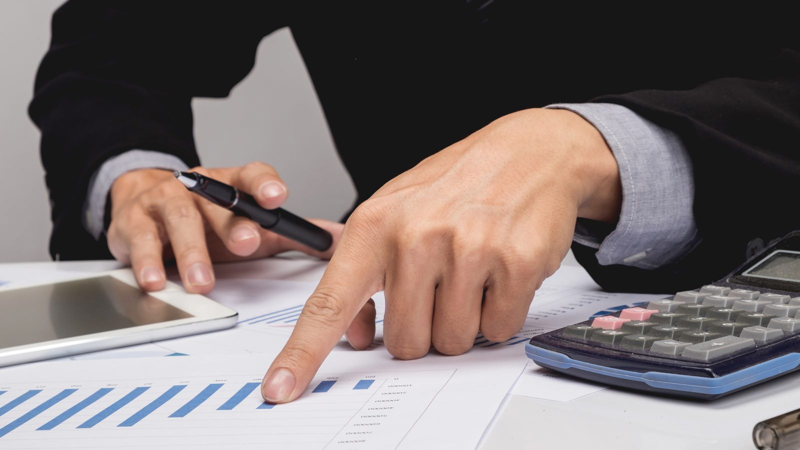 Manos sobre una mesa revisando gráficos y estados financieros